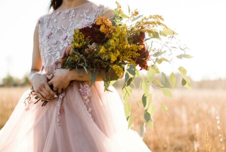 woman in pink and silver sleeveless dress holding bouquet of flowers