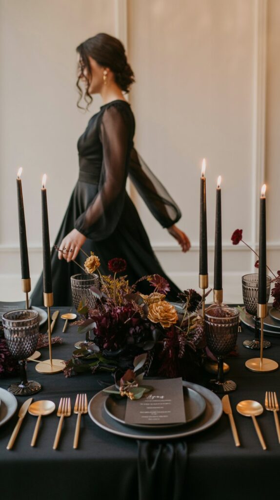 Moody fall wedding centerpiece with black linens, jewel-toned flowers, smoky glass, and candlelight.